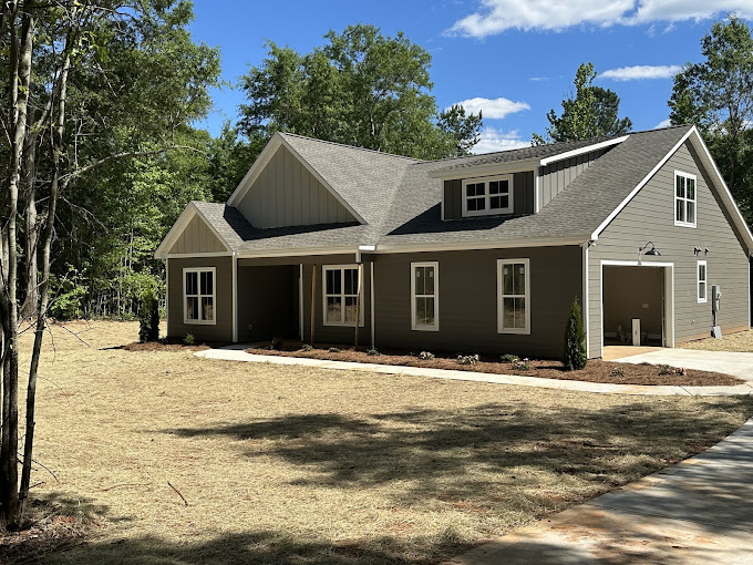 A house with a driveway and trees in the background