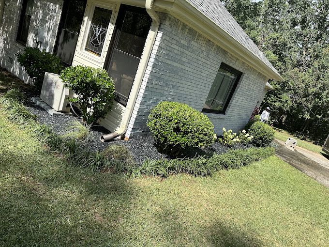 A house with a lawn and bushes in front of it