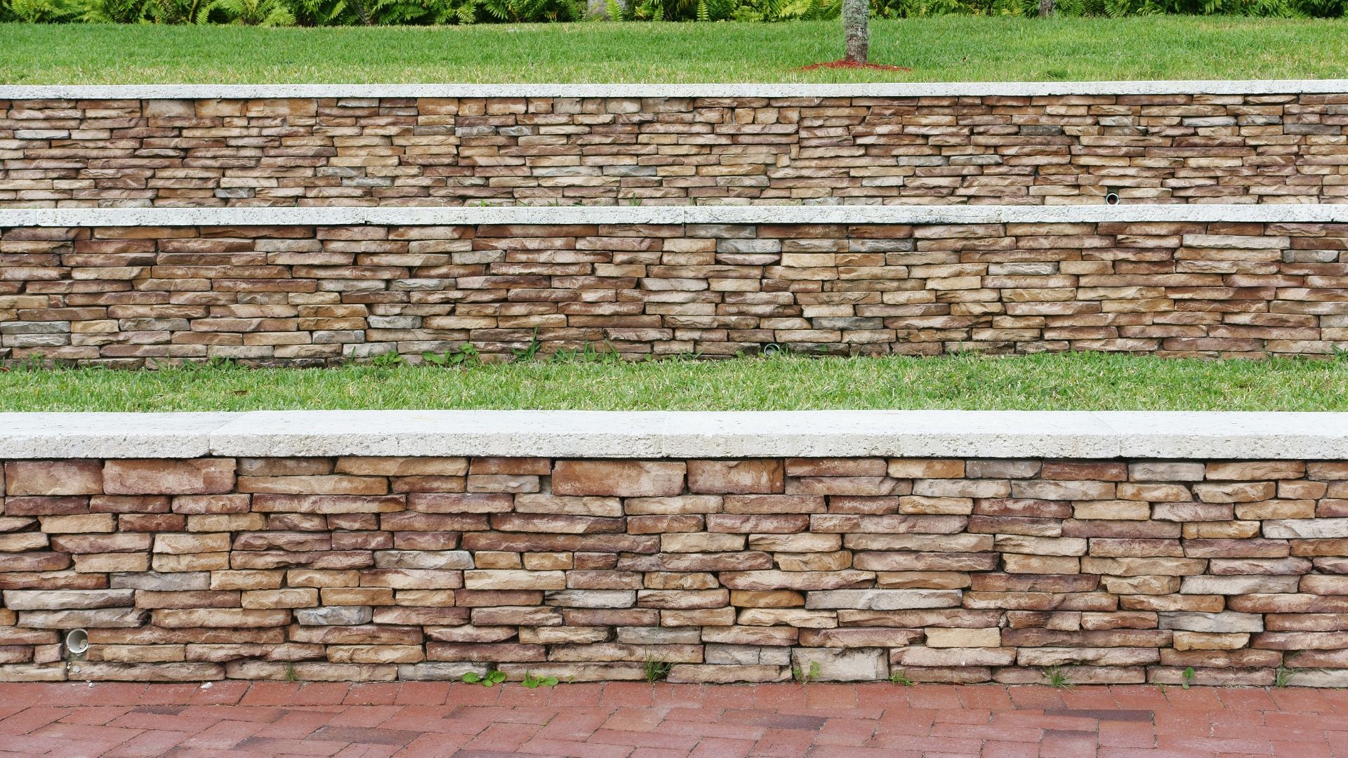 A person sitting on a bench next to a stone wall