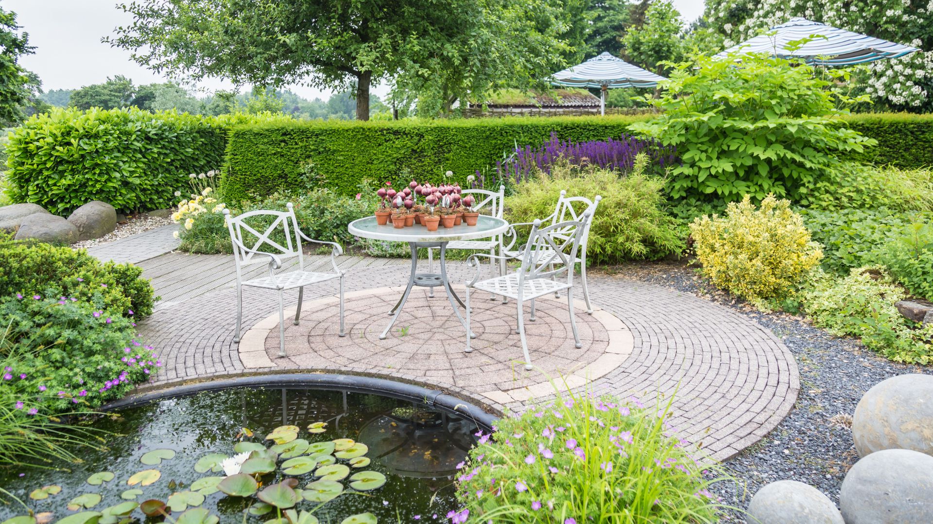 A patio with a table and chairs next to a pond